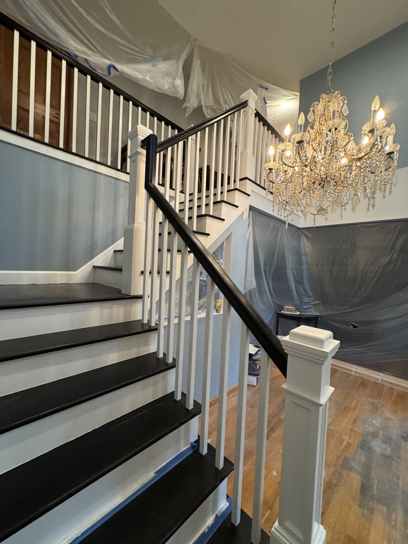 Finished staircase renovation with black-painted treads and white risers and spindles
